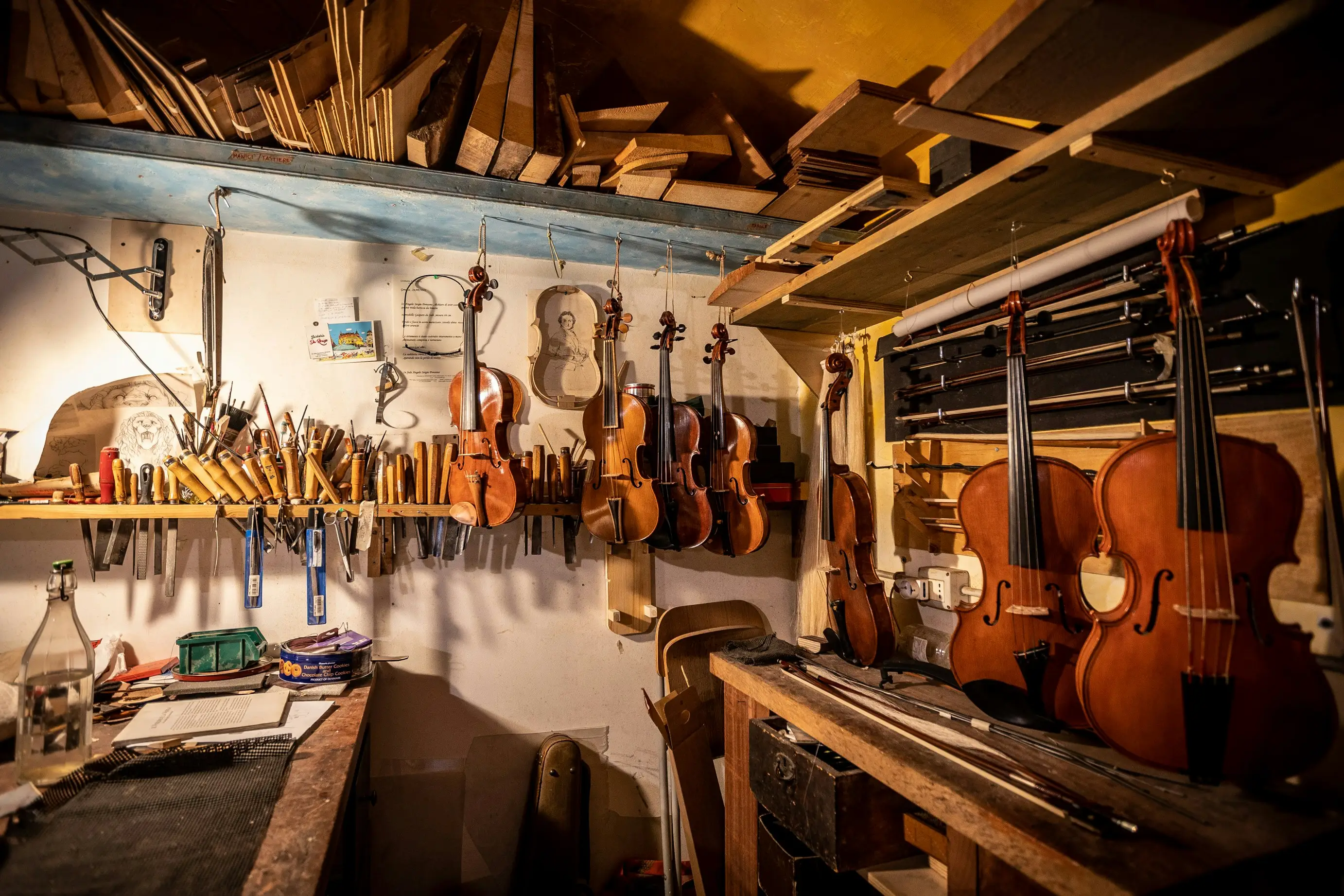 Atelier de luthière baigné d'une lumière chaude rasante, instrument en cours de fabrication sur l'établi